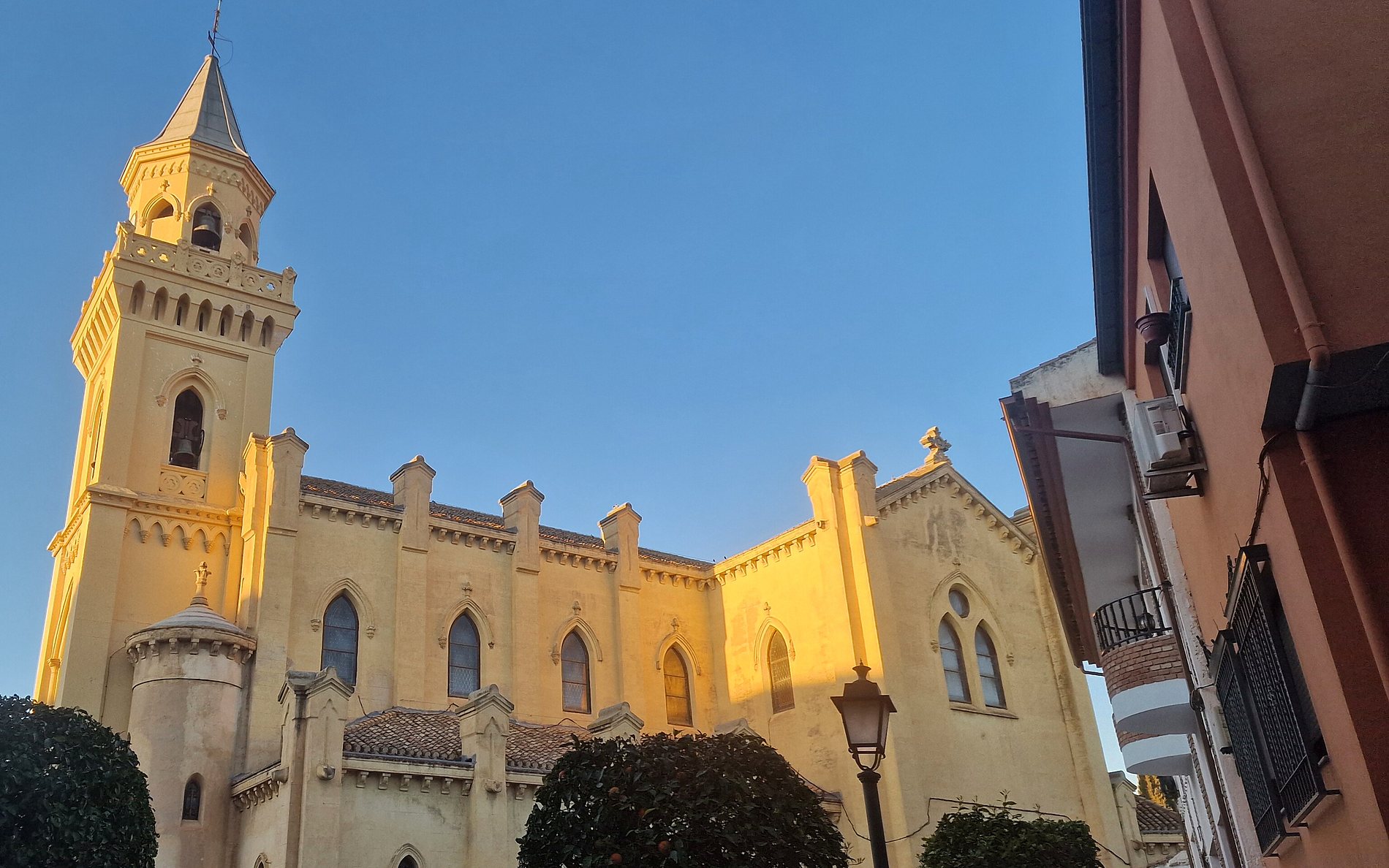 La iglesia parroquial vista desde la calle, entre los naranjos de la plaza